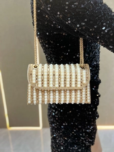 Detail of luxury gold evening clutch with pearls, rhinestones, and metallic chain strap