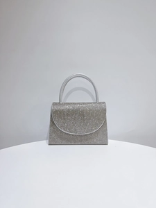 Close-up of silver rhinestone evening bag with trapezoidal body and diamond handle