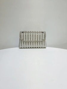 Detail of luxury pearl and rhinestone evening bag with elegant silver chain and vertical stripes