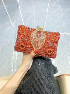Close-up of luxury red evening clutch with rhinestones and gold clasp detail