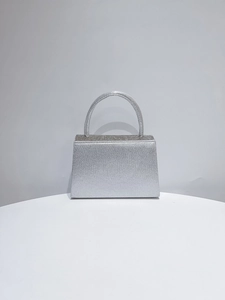 Detail of silver evening clutch featuring sparkling fabric and sparkling rhinestone lid