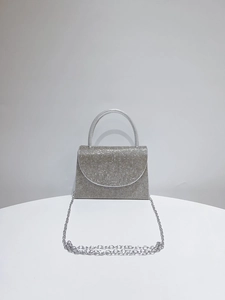 Detailed view of silver rhinestone evening clutch with curved handle and metal chain strap