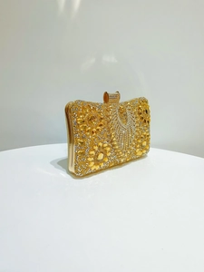 Close-up of golden luxury clutch bag with shimmering crystals and elegant flower pattern