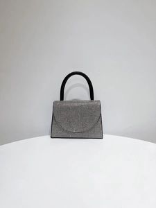 Close-up of sparkling silver rhinestones and black handle on elegant evening clutch bag