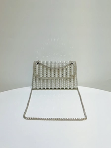 Close-up of elegant evening bag with vertical pearl rows and sparkling rhinestones