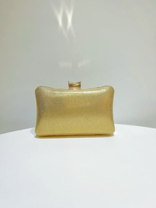 Macro shot of elegant champagne gold glitter evening clutch with intricate metal carved clasp