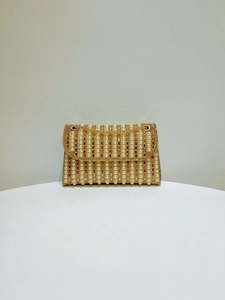 Close-up of evening clutch bag with vertical rows of white pearls and sparkling crystals