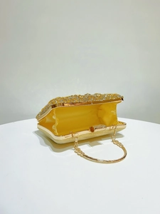 Detail of elegant gold evening clutch showing shiny rhinestones and yellow satin lining