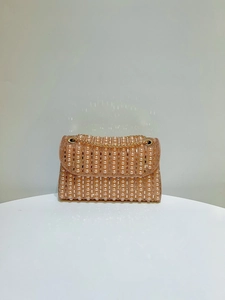 Detail of pink pearl evening bag featuring striped faux pearls and gold chain strap