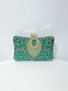 Detailed macro view of emerald rhinestone patterns and gold clasp on luxury clutch