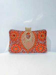 Close-up of red evening clutch featuring intricate crystal flower patterns and gemstone clasp