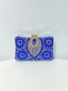 Detail of luxury royal blue clutch with inlaid rhinestones and gold tassel decoration