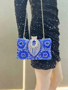 Detail of royal blue evening clutch featuring luxury rhinestones and golden tassels