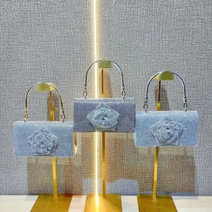 Detail of crystal evening clutch with 3D floral accent and metallic ring handle