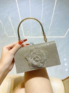 Detail of evening clutch featuring crystal-encrusted roses and golden circular metal handle