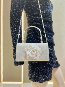 Detail of silver rhinestone evening clutch with 3D rose and metallic handle