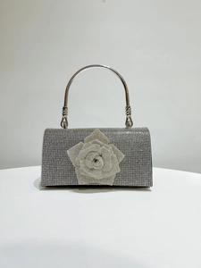 Close-up of silver evening bag with sparkling crystal rhinestones and a 3D rose detail