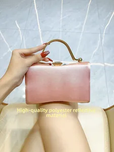 Detail of pink satin evening clutch bag featuring elegant gold metal handle and crystal clasp