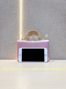 Pink satin evening clutch with gold handle showing size comparison with a smartphone
