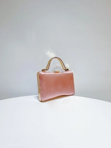 Detail of pink satin evening clutch featuring a rhinestone handle and crystal clasp