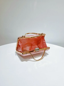 Detail view of pink satin clutch bag interior with golden chain strap and jewel clasp