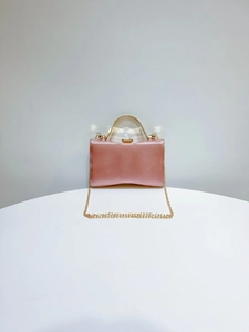 Close-up of pink satin evening clutch with golden handle and fine chain strap