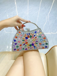 Macro detail of luxury evening clutch featuring colorful crystals and a silver metal ring handle