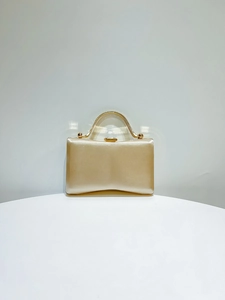 Detailed shot of champagne gold satin evening clutch with metallic round top handle