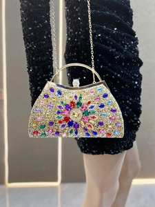 Close-up of luxury evening clutch with colorful rhinestones and gold metal handle