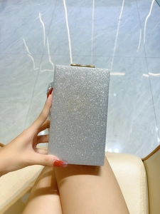 Détail de la pochette à paillettes argentées avec fermoir doré tenue à la main