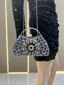 Close-up of luxury evening clutch with crystal sunflower motif and round handle