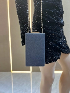 Détail d'une pochette de soirée pailletée noire avec chaîne dorée et fermoir chic