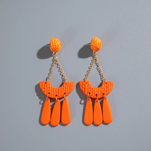 Detail of orange woven clay earrings with crescent shape and bohemian tassel pendants