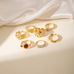 Lot de 7 bagues dorées en alliage avec pierres vintage et perles sur fond en soie blanche