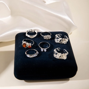 Détail d'un lot de 7 bagues en argent avec pierres orange sur support en velours bleu