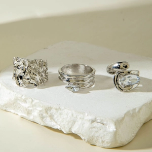 Détail de trois bagues géométriques argentées avec zircons marquise sur pierres blanches