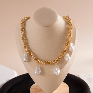 Detail of chunky gold chain necklace with five dangling baroque pearls on a display