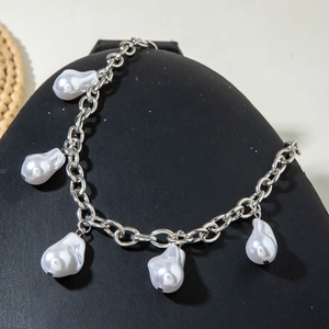 Detail of silver chain necklace featuring five white baroque pearls on a black display