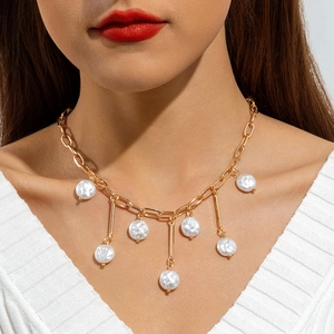 Detail of layered gold chain necklace featuring white pearls and vertical metal bars