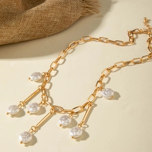 Detail of chunky gold chain necklace with baroque pearls and metal bar pendants