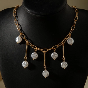 Close-up of gold chain necklace with baroque pearls and geometric charms on a neck bust