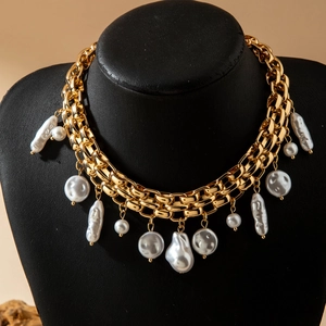 Detail of chunky gold chain necklace with layered baroque pearls on a black bust