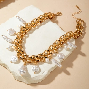 Detail of gold flat chain necklace featuring baroque pearls and classic lobster clasp