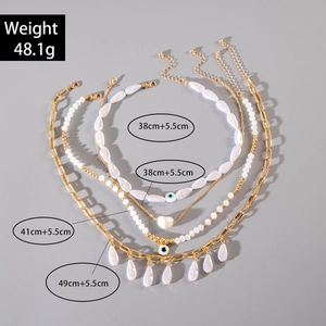 Bohemian multilayer gold necklace set with heart charms and faux pearls on gray background