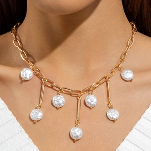 Gold chunky chain necklace with irregular pearl pendants and metal bars worn by a model