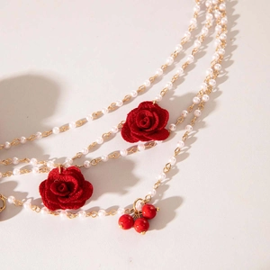 Détail d'une chaîne de taille multicouche en perles avec roses rouges et accents dorés