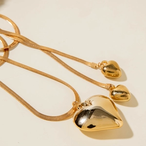 Primer plano detallado de un collar de cadena de serpiente con dijes de corazón