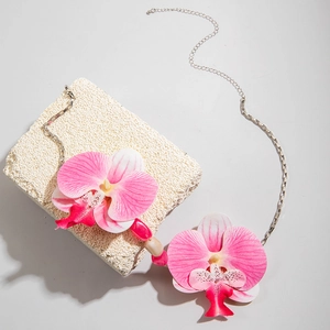 Détail du collier de fleurs d'orchidées roses avec chaîne argentée sur pierre