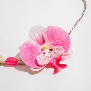 Vue rapprochée du pendentif orchidée rose et blanc sur une chaîne argentée texturée