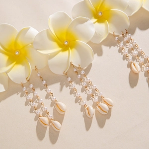 Détail d'une chaîne de taille multicouche en perles avec fleurs de frangipanier et coquillage